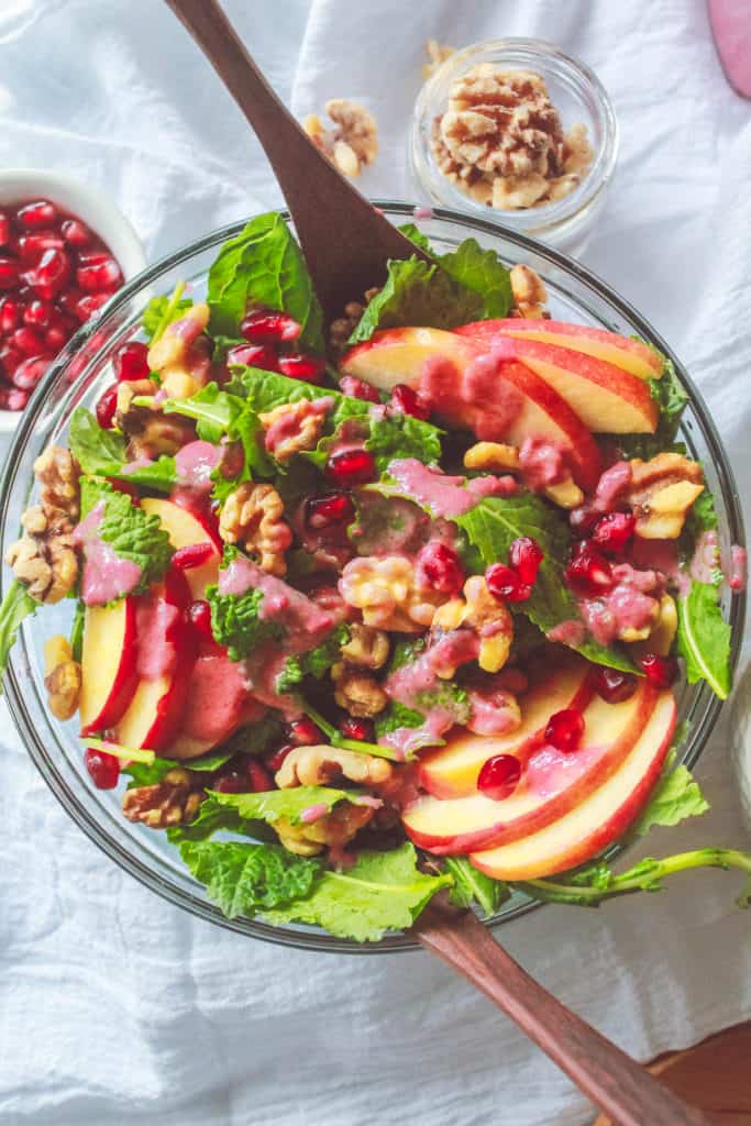 Healthy and refreshing winter salad with kale, pomegranates, walnuts, and apples that makes a perfect side for stews, soups, casseroles, and more!