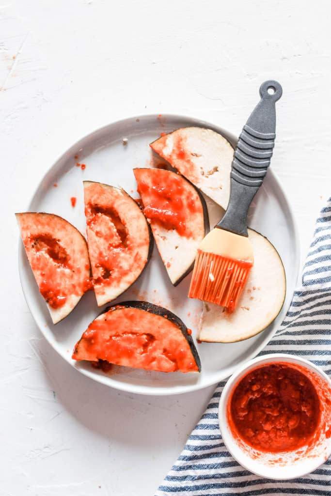 Super simple, healthy stovetop harissa eggplant recipe topped with a delicious mint yogurt sauce. Serve on its own as a side or mix in salads or pasta! #eggplant #harissa